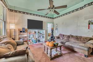 Living room with carpet and a ceiling fan