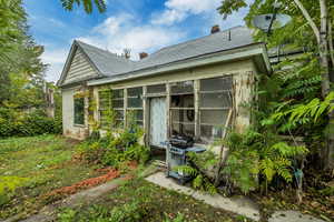 Back of house featuring a sunroom, a chimney, and a shingled roof