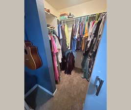 Spacious closet featuring dark colored carpet