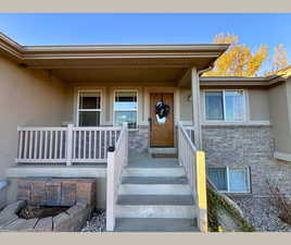 Property entrance featuring stucco siding, covered porch, and brick siding