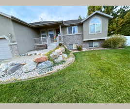 View of front of home with stucco siding, covered porch, brick siding, and a front lawn