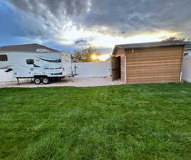 Yard at dusk with a fenced backyard and an outdoor structure