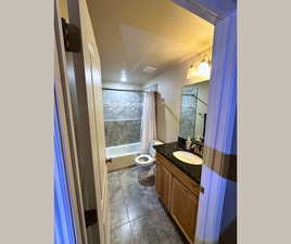 Full bath with vanity, shower / bath combination with curtain, a textured ceiling, and dark tile patterned floors