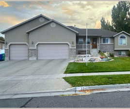 Single story home with stucco siding, a front yard, stone siding, concrete driveway, and a garage