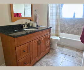 Bathroom featuring vanity, shower / bath combo, and light tile patterned flooring
