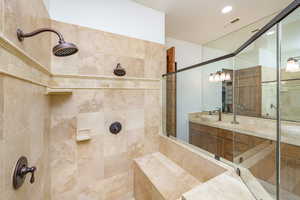 Full bath featuring tiled shower, double vanity, and recessed lighting