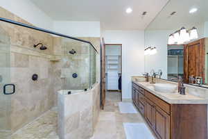 Full bathroom with a walk in closet, double vanity, a shower stall, recessed lighting, and light tile patterned flooring
