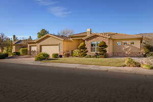 Ranch-style home featuring stone siding, stucco siding, driveway, a garage, and a front yard