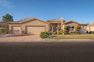 View of front of house with stucco siding, stone siding, a garage, concrete driveway, and a front yard