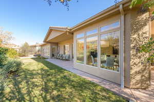 Rear view of property with a yard, stucco siding, and a patio