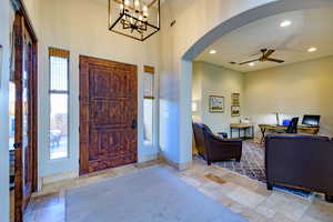 Entryway with ceiling fan, recessed lighting, stone tile flooring, arched walkways, and a chandelier
