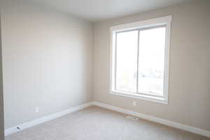 Carpeted spare room with baseboards