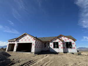 Unfinished property featuring a mountain view, roof with shingles, and an attached garage