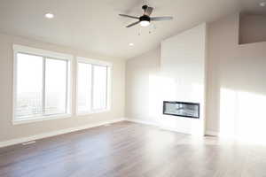 Unfurnished living room with a fireplace, lofted ceiling, light wood-type flooring, a ceiling fan, and recessed lighting