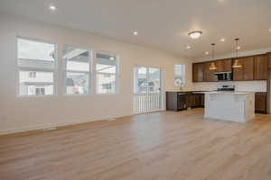 Kitchen featuring light countertops, pendant lighting, light wood finished floors, open floor plan, and recessed lighting