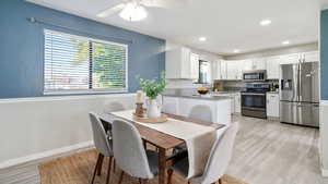 Dining space with a textured wall, light wood-style flooring, recessed lighting, and ceiling fan