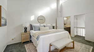 Bedroom with dark carpet, a towering ceiling, and ensuite bathroom
