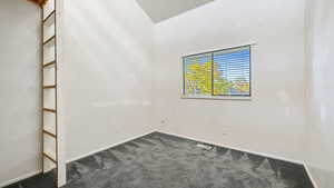 Unfurnished room featuring dark carpet and baseboards