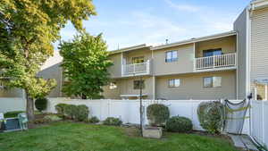 Rear view of house with a fenced backyard and a balcony