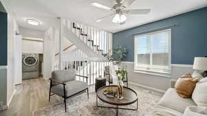 Living area with light wood-style flooring, a ceiling fan, stairway, and washer / clothes dryer