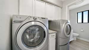Washroom featuring light wood finished floors, a textured wall, and washing machine and clothes dryer