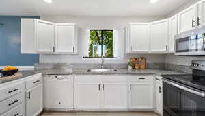 Kitchen featuring appliances with stainless steel finishes, white cabinetry, recessed lighting, and light wood finished floors
