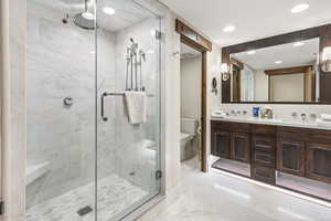Full bathroom featuring a marble finish shower, double vanity, light marble finish floors, and recessed lighting