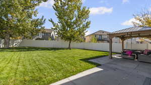 Fenced backyard with a gazebo, a patio, and a residential view