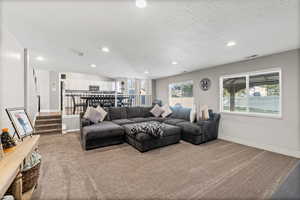 Carpeted living room with recessed lighting, a textured ceiling, and stairway