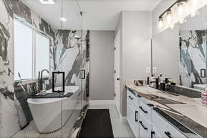 Bathroom featuring a marble finish shower, double vanity, a soaking tub, light tile patterned floors, and stone wall