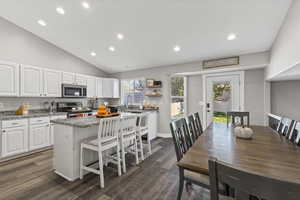Kitchen with dark stone counters, white cabinets, recessed lighting, a kitchen bar, and stainless steel appliances