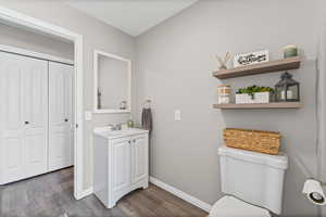 Half bathroom with vanity, dark wood-style flooring, and a closet