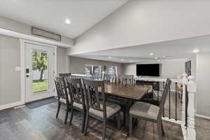 Dining room with lofted ceiling, recessed lighting, healthy amount of natural light, dark wood-style flooring, and a textured ceiling