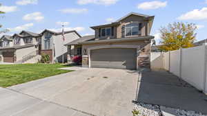 View of front of home with driveway, stone siding, a residential view, stucco siding, and a garage