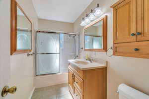Full bathroom with vanity, light tile patterned floors, and shower / bath combination with glass door