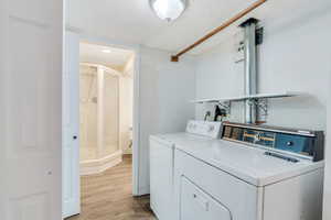 Laundry area with light wood-type flooring, a textured ceiling, and washer and dryer