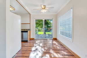 Unfurnished dining area featuring light wood finished floors, crown molding, and a ceiling fan