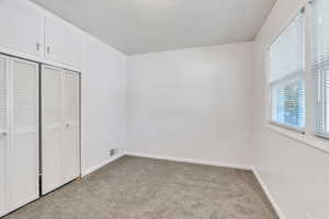 Unfurnished bedroom with light colored carpet and a closet