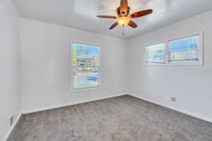 Carpeted spare room featuring baseboards and ceiling fan