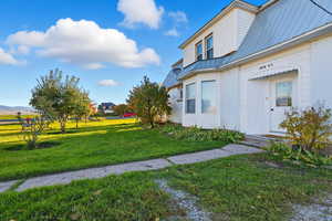 View of home's exterior with a metal roof and a lawn and entrance for mother in law suite