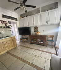 Living area with inlaid floor details, light tile patterned flooring, and a ceiling fan