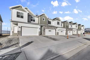 View of front of house featuring stone siding, concrete driveway, an attached garage, and a residential view