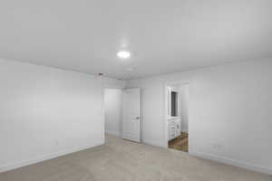 Unfurnished bedroom with light colored carpet and ensuite bathroom