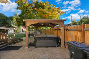 Fenced backyard with a hot tub, a gazebo, and a patio area