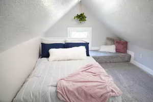 Carpeted bedroom featuring lofted ceiling and a textured ceiling