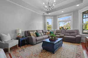 Living room featuring a tray ceiling, wood finished floors, plenty of natural light, and recessed lighting