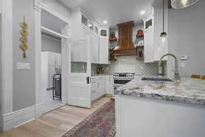 Kitchen featuring open shelves, light stone countertops, white cabinetry, and decorative backsplash