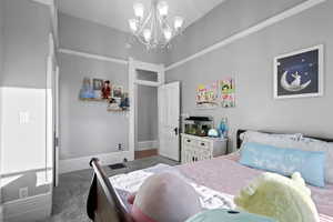 Carpeted bedroom with a chandelier and baseboards
