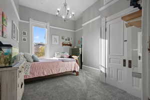 Carpeted bedroom featuring a chandelier and baseboards