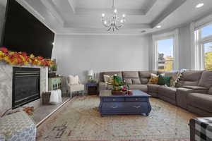 Living area featuring a premium fireplace, a chandelier, and a raised ceiling